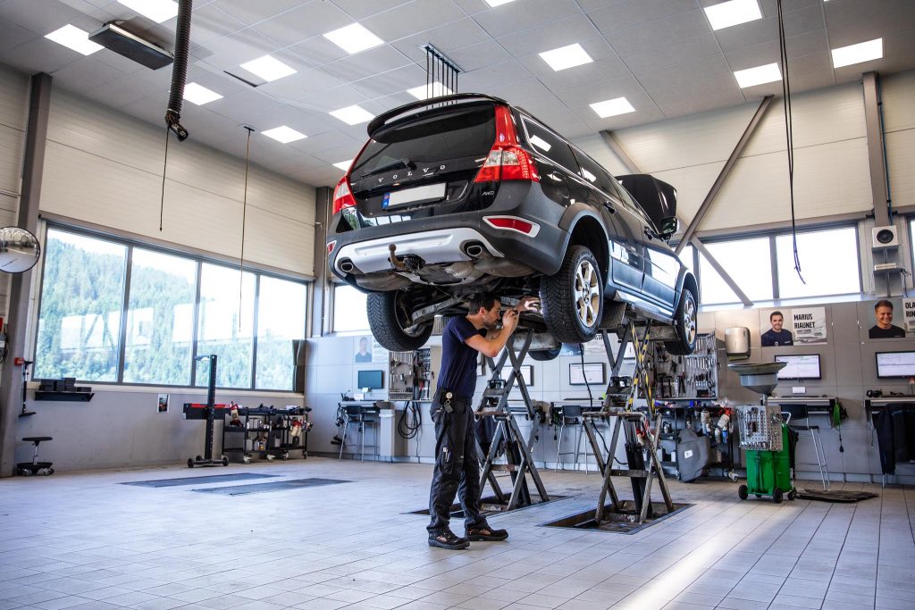 Mann undersøker hjulet på en hevet, sort Volvo