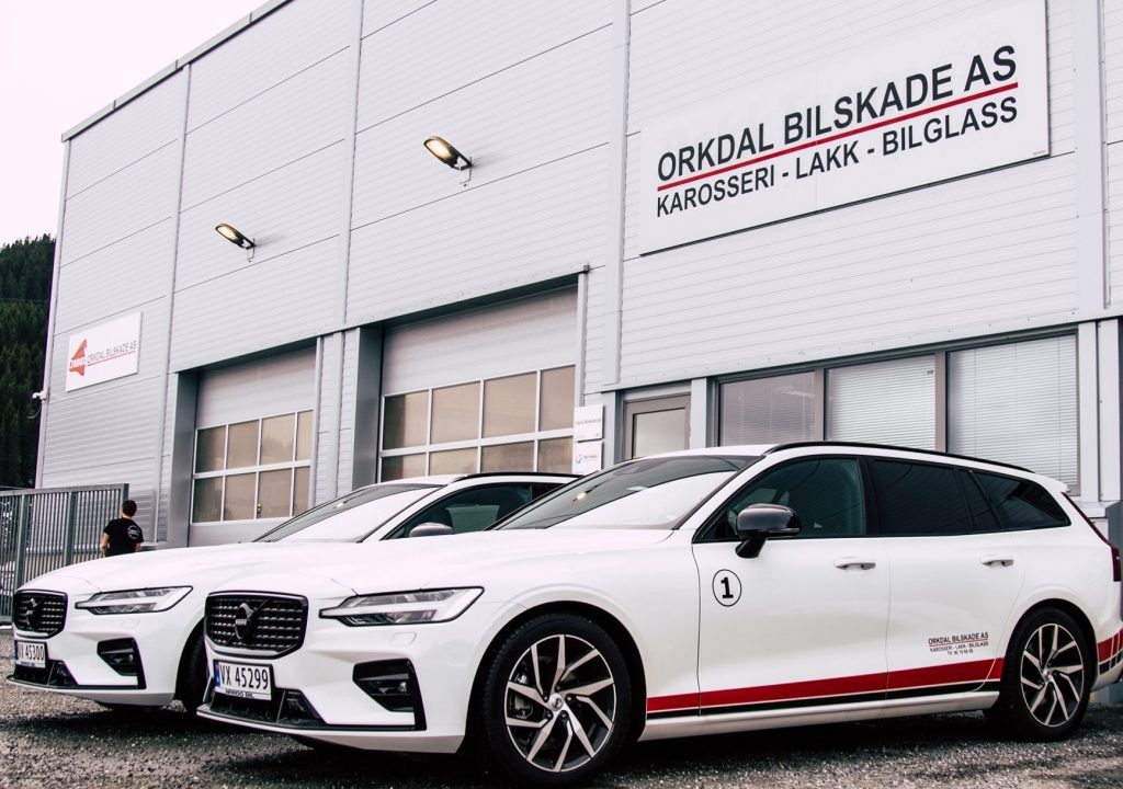 Hvite biler parkert utenfor verksted