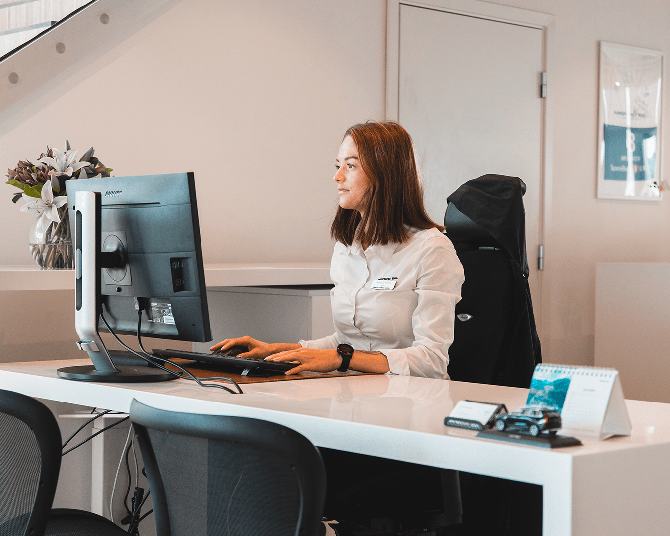 Kvinne sitter bak skrivepult og skriver på et tastatur