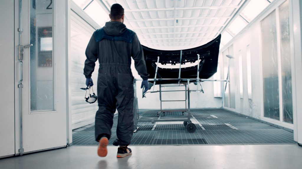 Mann i heldekkende dress med maske i hånden