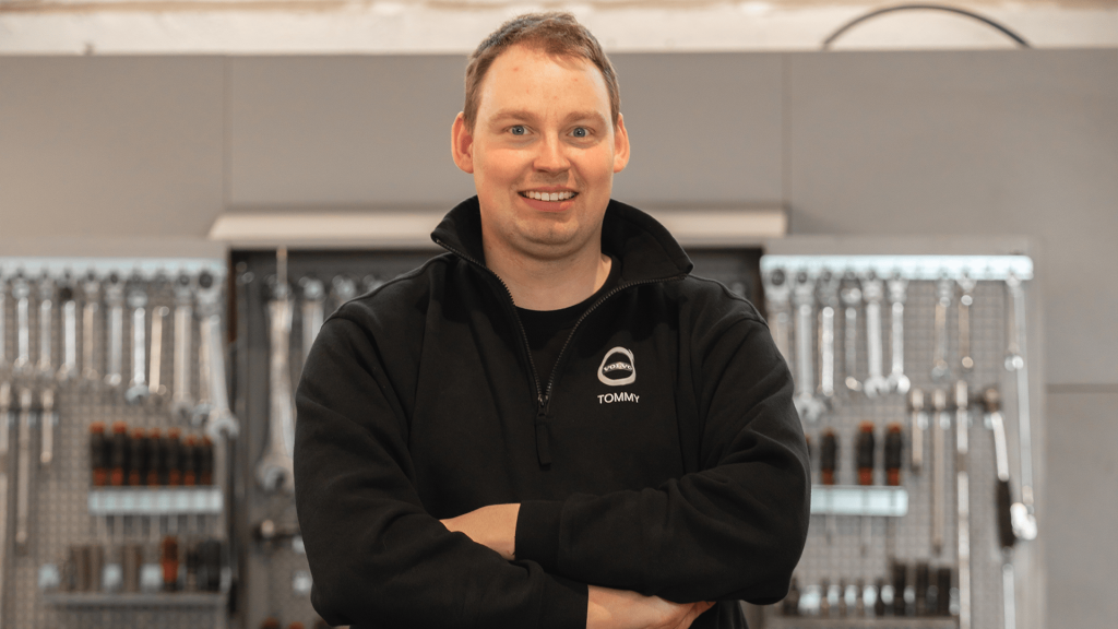 Mann i svart jakke på bilverksted