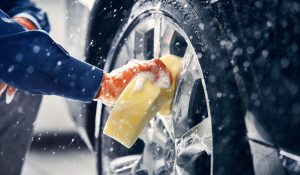 Felgen på et bilhjul vaskes med en gul svamp