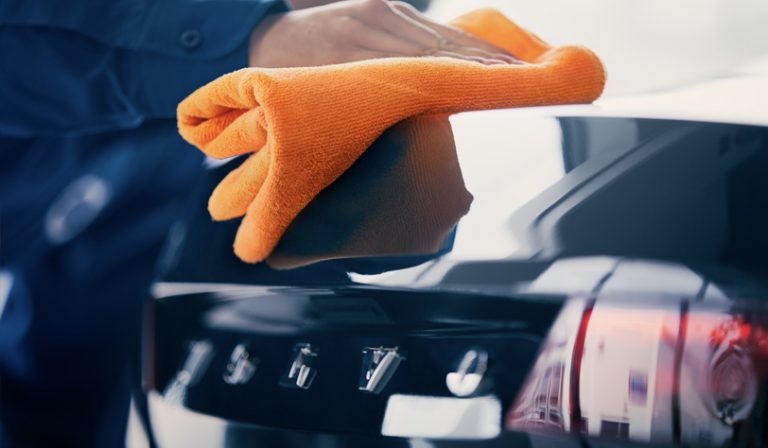 Svart bil poleres for hånd med klut