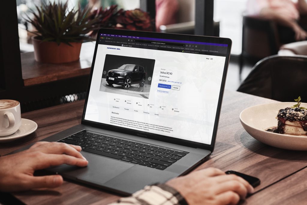 Bærbar datamaskin åpen på kafébord med bilside i nettleser