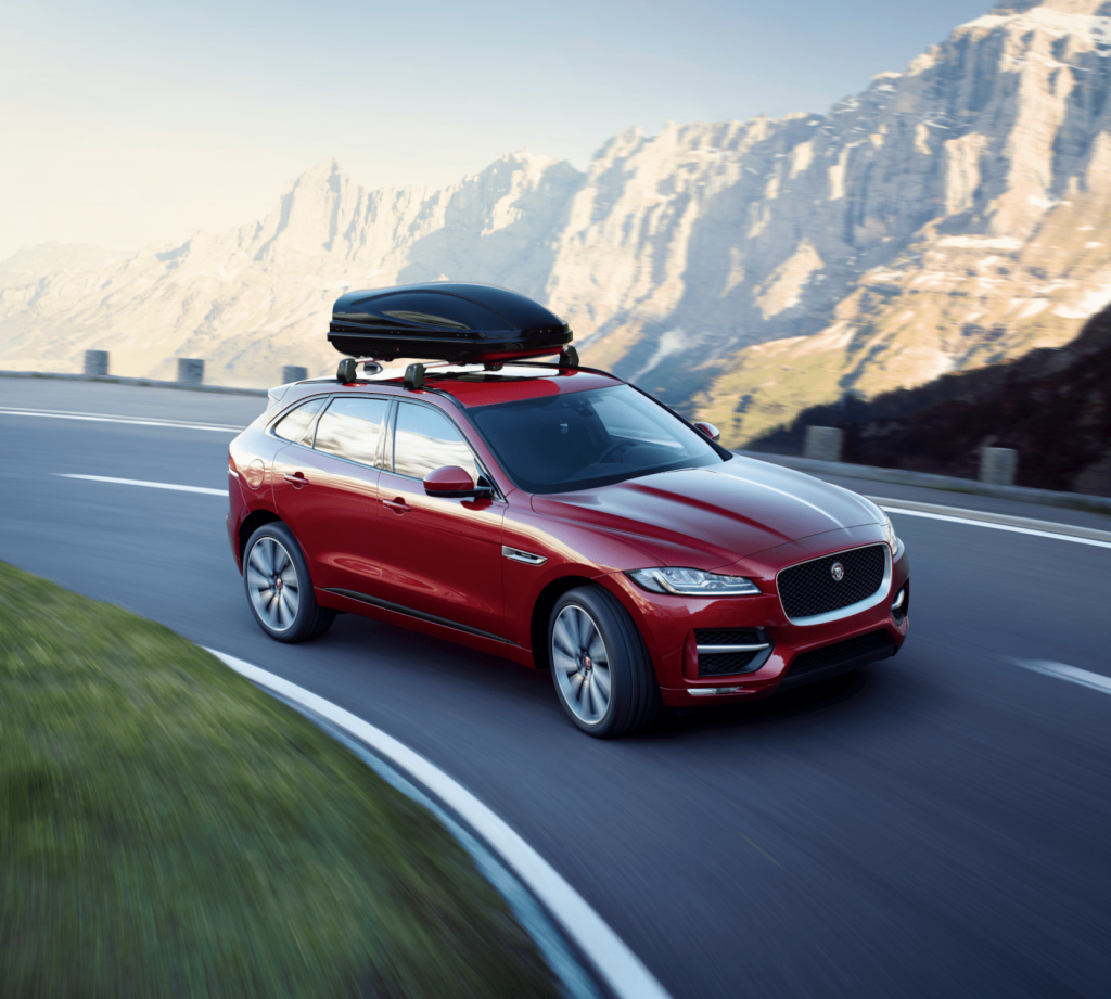 Røs bil med takboks i fart