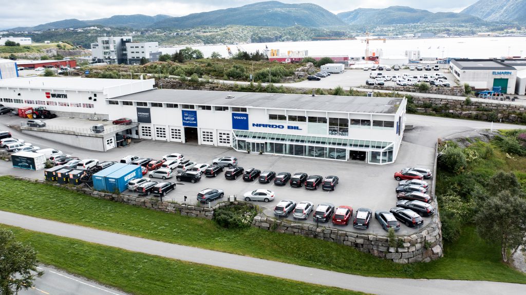 Stor, hvit bygning med mange parkerte biler utenfor