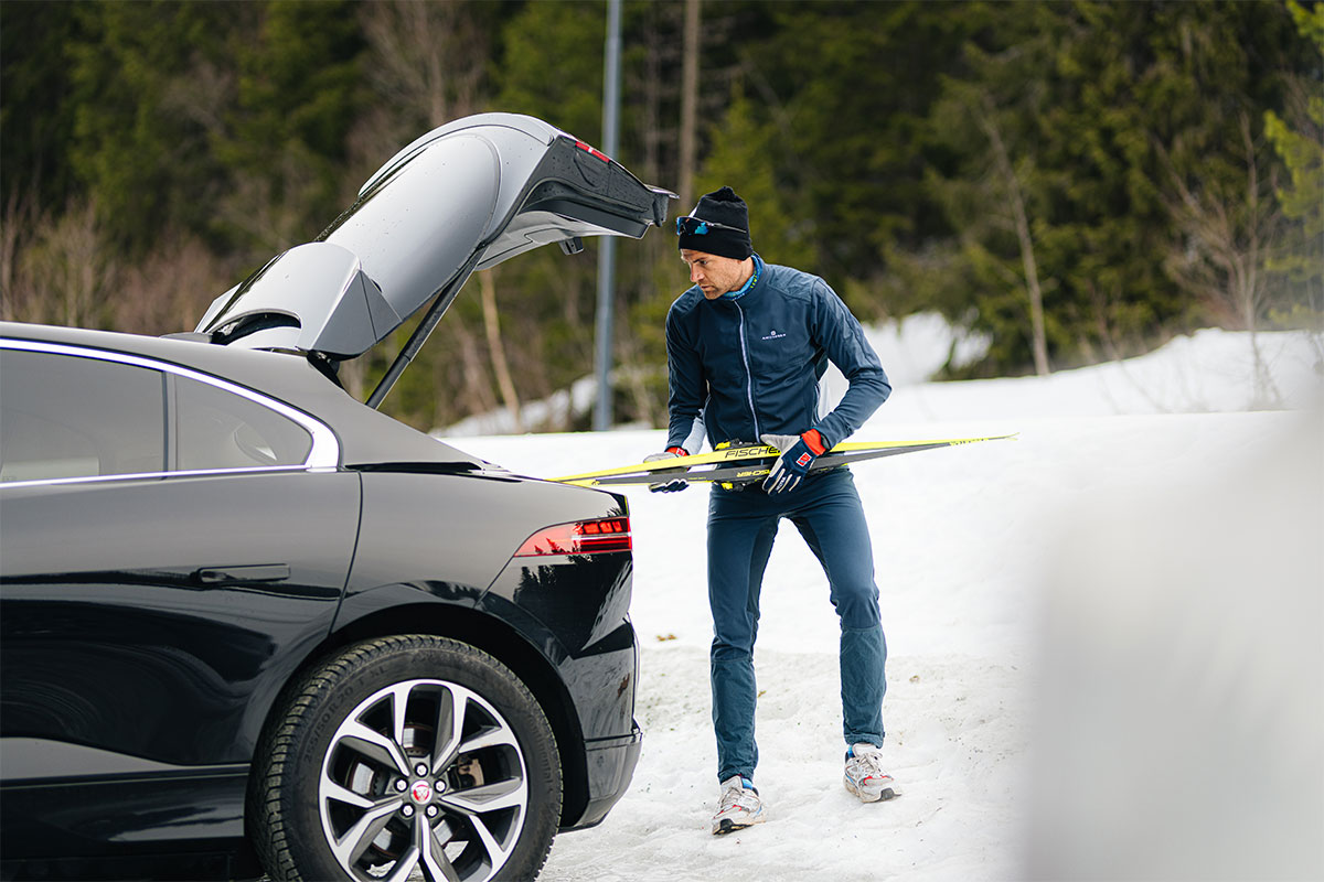 Niklas Dyrhaug legger langrennski inn bagasjerommet på en svart bil