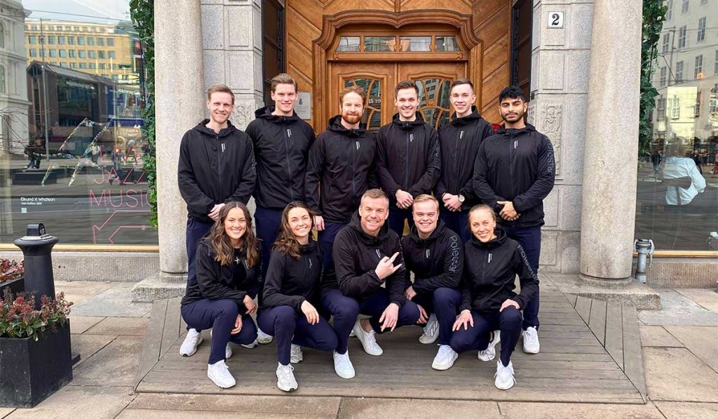 Gruppebilde av 11 polestaransatte utenfor en dr i like svarte jakker